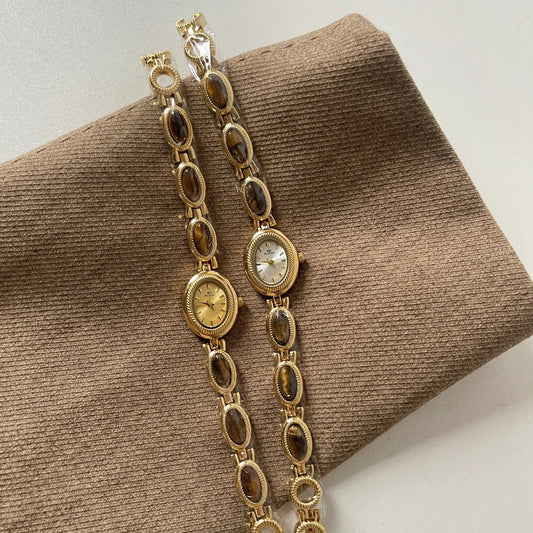 Gold chain watch on a brown textured surface