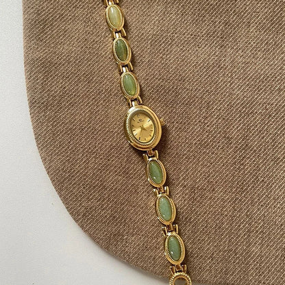 Gold bracelet with green gemstones on a brown fabric background