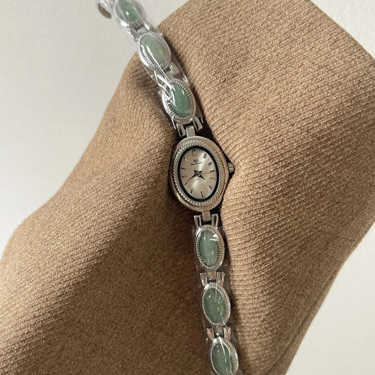 Silver bracelet with green stones on a beige fabric background