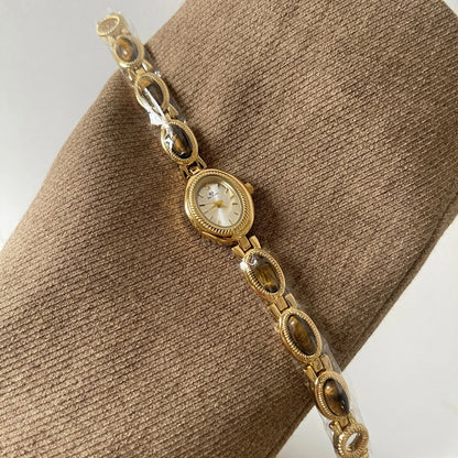 Gold bracelet with a watch face on a brown textured surface