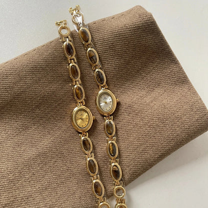 Gold chain watch on a brown textured surface