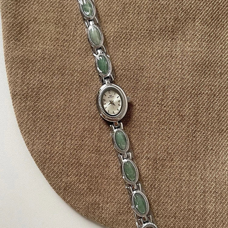 Silver bracelet with green stones on a brown surface