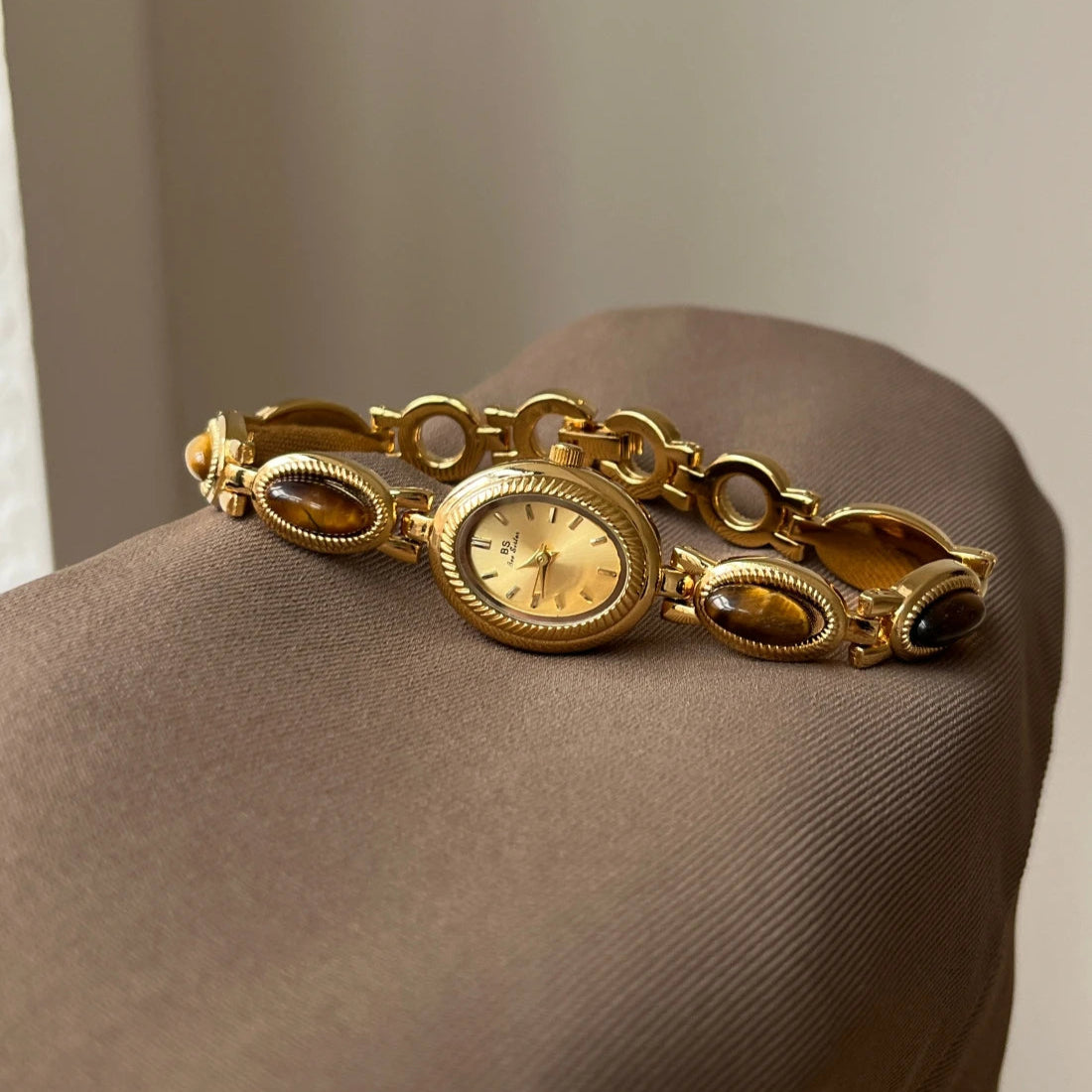 Gold bracelet with a clock face on a brown surface