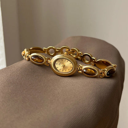 Gold bracelet with a clock face on a brown surface