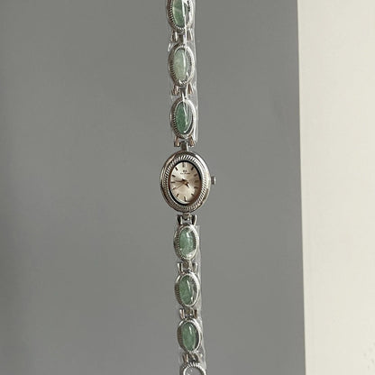 Silver bracelet with green gemstones on a gray background